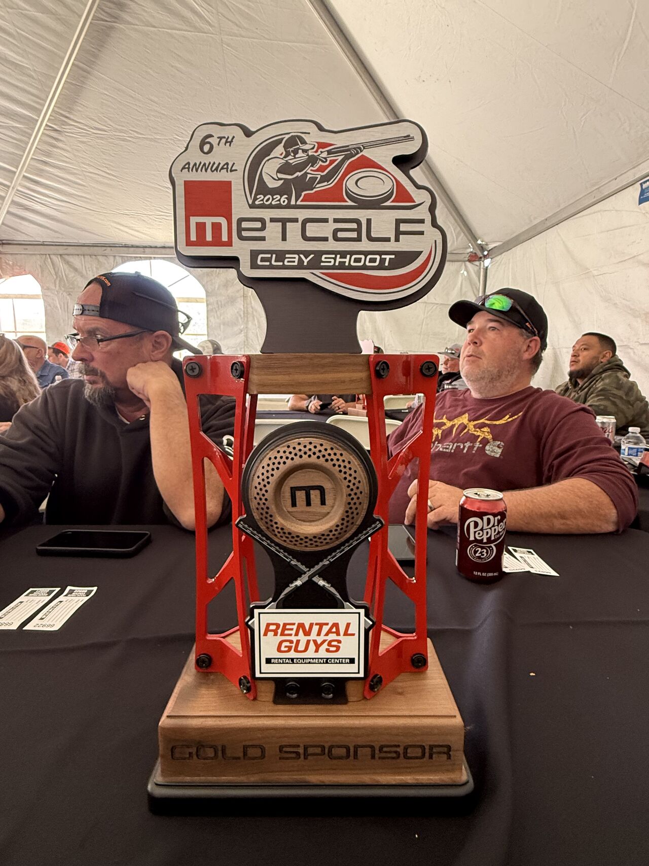 Metcalf Clay Shoot 2026 gold sponsor trophy from Rental Guys displayed on a table inside an event tent